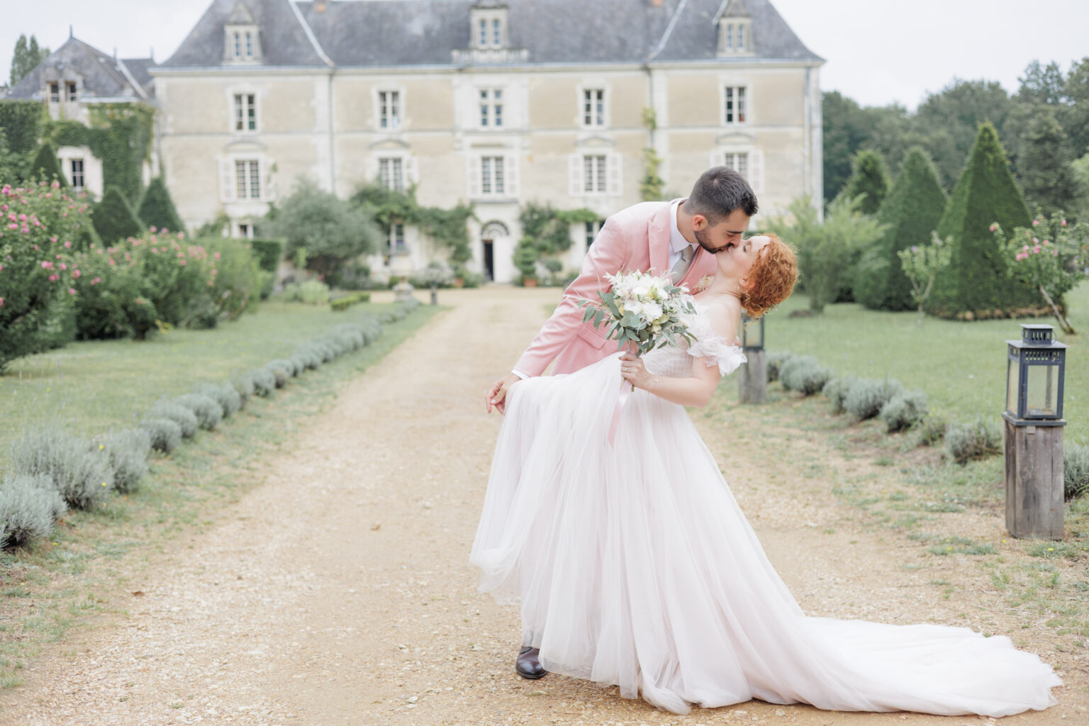 Photo de 2 mariés qui s'embrassent devant un château