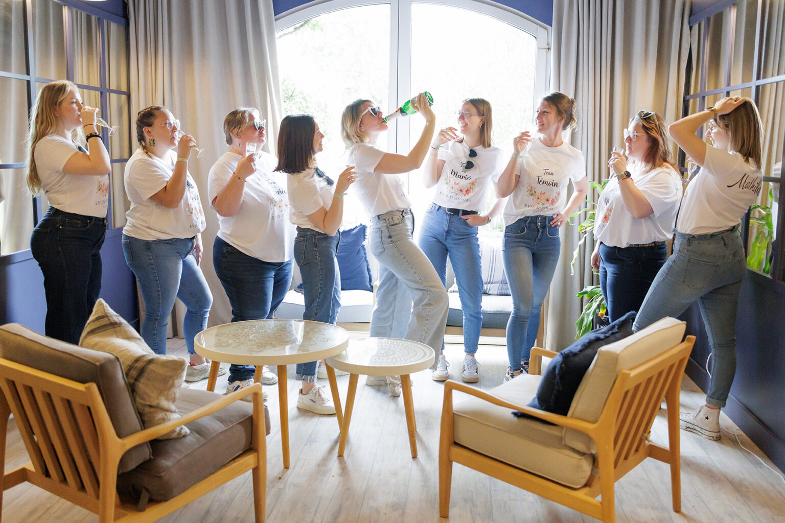 Photo d'une future mariée qui boit du champagne entourée de ses amies lors de son evjf